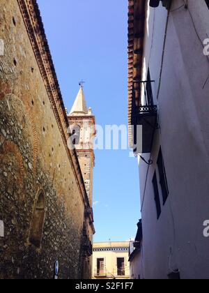 Zwischen zwei hohe Wände in einer engen Gasse ein Kirchturm lugt durch Alájar in Andalusien Spanien Stockfoto