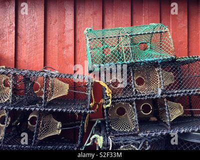 Leere crab Töpfe oder Traps bis vor einem rot lackierten Holz- in Valle, Norwegen Schuppen gestapelt. Stockfoto