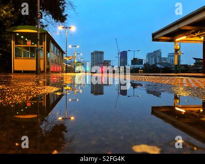 Reflexionen in einem regen Pfütze auf einem Bahnsteig, Cardiff. Stockfoto