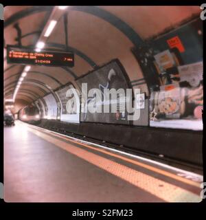 U-Bahnstation Plattform mit U-Bahn in Abstand und digitale Information Board Stockfoto