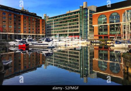 Boote und Gebäude in der noch Wasser von St Katherine's Dock in der Londoner City wider Stockfoto