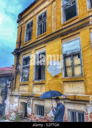 Ein Mann mit einem schwarzen Dach steht vor einem alten, historischen Gebäude in der Altstadt von Plovdiv, Bulgarien. Stockfoto