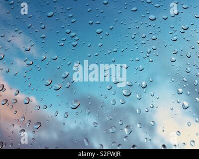 Regentropfen auf Fenster mit blauen Himmel im Hintergrund Stockfoto