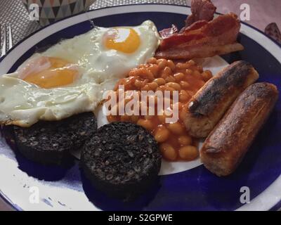 Ein englisches Frühstück mit Spiegelei, gebackene Bohnen, Würstchen. Speck und Blutwurst. Stockfoto
