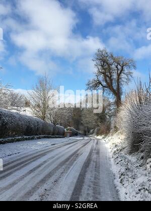 Verschneite Landstraße bei Sonnenschein in der Nähe von Tarporley, Cheshire, England Stockfoto