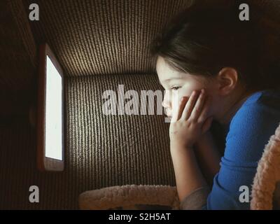 Junge Kind an Tablet Bildschirm schaut in der Dunkelheit Stockfoto