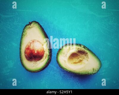 Avocado Halbieren mit Pit auf blauem Hintergrund sichtbar Stockfoto