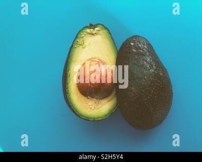Avocado Halbieren mit Pit auf blauem Hintergrund sichtbar Stockfoto