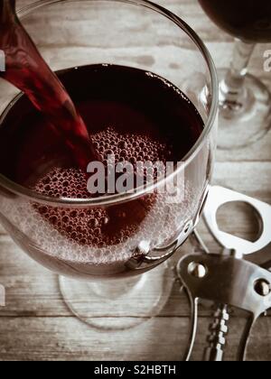 Rotwein wird in ein Glas gegossen Stockfoto