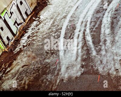 Graffiti neben Reifenspuren auf eisglatter Fahrbahn Stockfoto