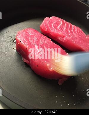 Frischer Thunfisch Steaks in einer heißen Pfanne mit Öl gebürstet auf einem der Stücke gebratene Stockfoto
