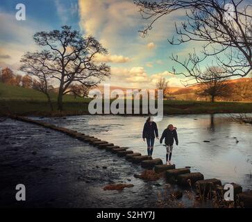 Zwei Mädchen gehen über Trittsteine auf Whitewell Stockfoto
