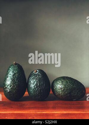 Noch immer leben von drei Avocados auf Holz- Oberfläche mit grauer Hintergrund Stockfoto