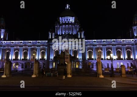 Belfast City Hall, Nordirland bei Nacht - ein denkmalgeschütztes Gebäude, 1906 fertiggestellt und 2009 renoviert. Dieses majestätische Gebäude wird nachts oft fantasievoll beleuchtet. Im Inneren sind viele feine Merkmale. Stockfoto