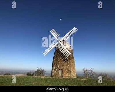 Eine schöne Landschaft mit einer Windmühle auf einem hohen Hügel mit toller Aussicht und strahlend weißer drone Schweben über die Segel. Stockfoto