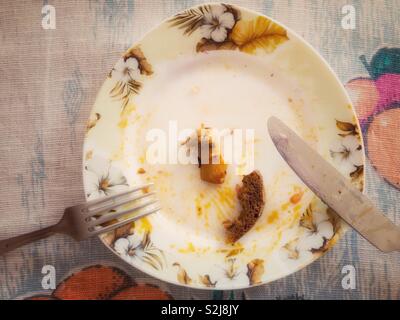 Ansicht von oben auf eine schmierige Platte mit Brot und Rindfleisch Reste zwischen Messer und Gabel Stockfoto