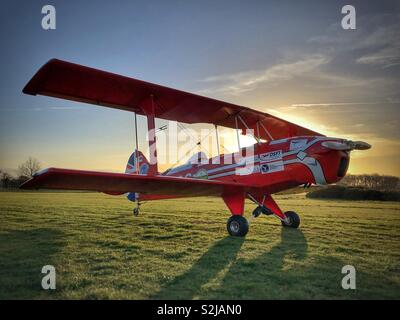 Doppeldecker bei Sonnenuntergang bei Sonnenuntergang auf dem Gras Flugplatz Stockfoto