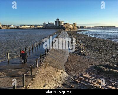 Zwei Wanderer über die Marine Lake Causeway in Weston-super-Mare, Großbritannien auf einem sonnigen Nachmittag. Stockfoto