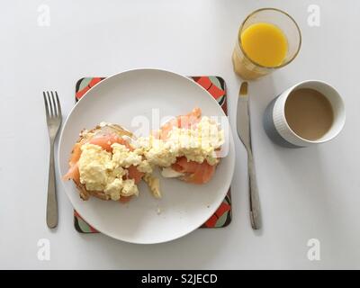 Geräucherter Lachs und Rührei auf einem Bagel, mit einem Glas Orangensaft und Kaffee in Royal Copenhagen cup Stockfoto