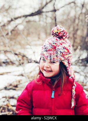 Portrait von LÄCHELNDEN 3 Jahre altes Mädchen mit Hut und Mantel im Winter im Wald Stockfoto