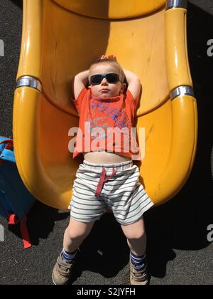 Drei Jahre alten Jungen bei Sonnenbrillen chillen an einem sonnigen Tag an der Unterseite einer Folie Stockfoto