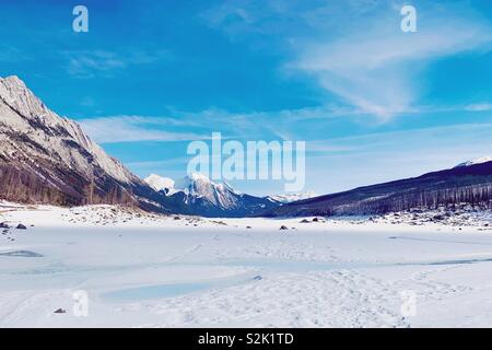 Schnee bedeckt Medicine Lake im Jasper Nationalpark auf einer Feder sonnigen Tag eingefroren. Stockfoto