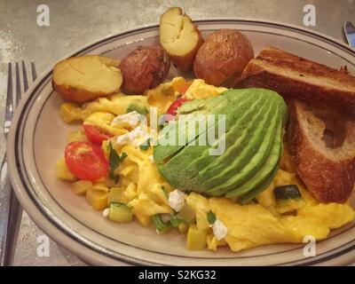 Pflanzliche Rühreier mit Avocado, Bratkartoffeln, und geröstetem Brot Stockfoto