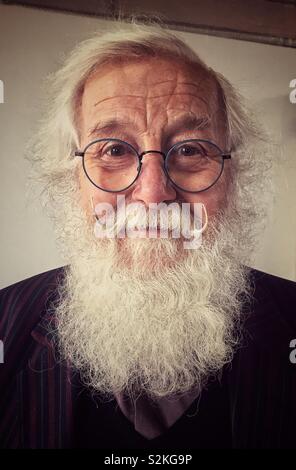 Lächelnd älterer Mann mit weissen buschigen Bart und Stahl umrandeten Brille. Stockfoto