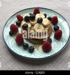 Pfannkuchen mit Himbeeren, Heidelbeeren und Banane und Nieselregen von Ahornsirup Stockfoto