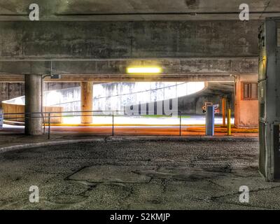 Schmutzige Alte und vernachlässigten innerstädtischen Parkgarage mit einer Rampe beleuchtet mit natürlichem Licht. Stockfoto