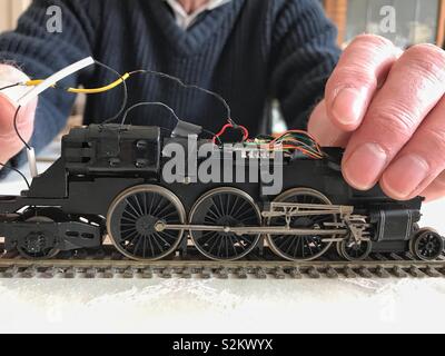 Ein Mann arbeitet auf die Elektrik auf ein Modell Lokomotive. Stockfoto