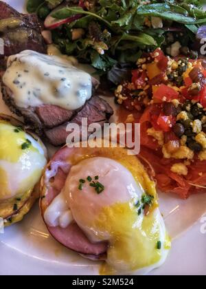 Platte mit köstlichen Brunch Buffet essen Eier Benedikt, gebackenes Lamm mit Joghurt Sauce, Salat. Stockfoto
