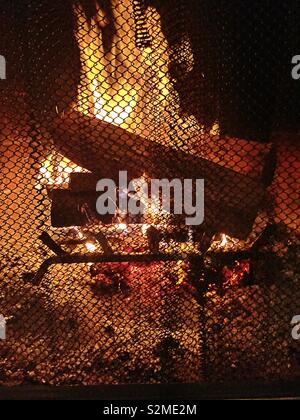 Prasselnden Feuer als durch den Bildschirm zu einem Wohngebiet Kamin gesehen, USA Stockfoto