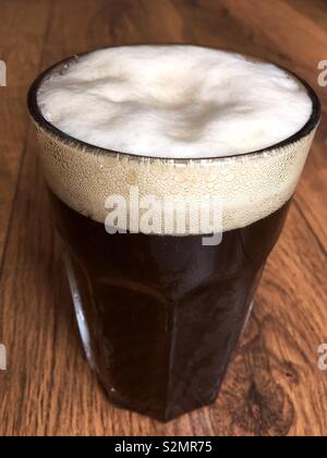 Glas oder Pint Ale Bier mit einer schaumigen Kopf auf einem Holztisch Stockfoto