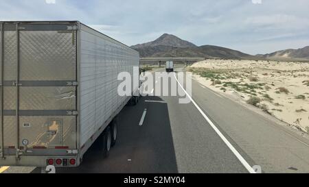 Weiß Lieferung vorbeifahrende Lastwagen auf Autobahn fahren Sie durch bergige Region in Kalifornien Stockfoto