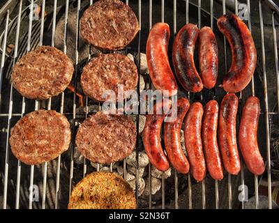 Burger und Würstchen kochen auf einem Holzkohlegrill Stockfoto