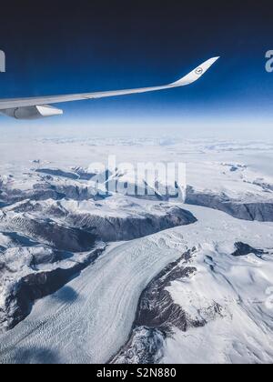 Grönland aus dem Flugzeug Fenster. Flugzeugflügel im Blick und Luftaufnahme der schneebedeckten Gletscher unterhalb Stockfoto