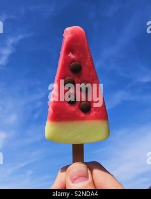 Wassermelone Eis am Stiel gehalten bis zu blauen Himmel. Stockfoto