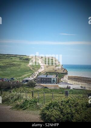 Dutzende von Touristen riskieren ihr Leben gehen und sitzen auf der Klippe am Birling Gap in Eastbourne Stockfoto