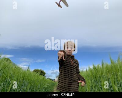 7 Jahre alten Jungen werfen ein Modellflugzeug in einem Feld Stockfoto