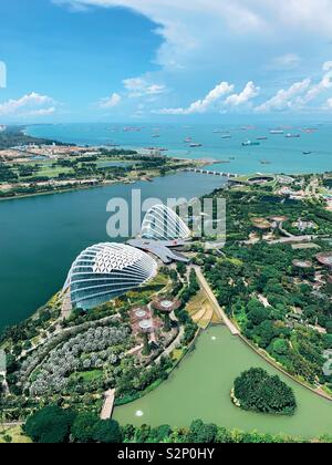 Singapur. Blick von der 57th. Etage auf den Sand der Marina Bay mit Gärten an der Bucht, Super Trees, Flower Dome, Cloud Forest und Schiffen im Hafen