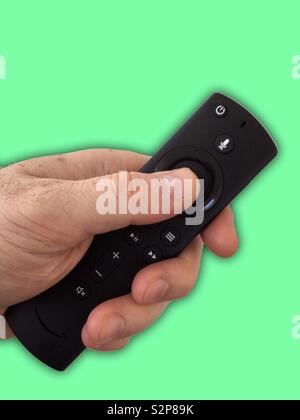 Männliche Hand hält eine Amazon-Stick-Fernbedienung. Coronavirus tv. Stockfoto