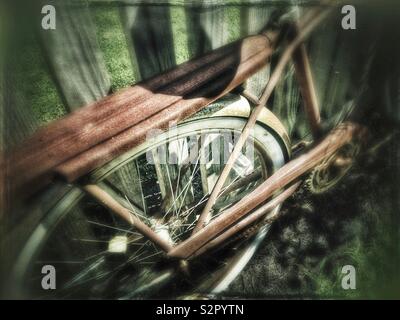 Rusty Vintage Fahrrad gegen einen hölzernen Zaun geparkt Stockfoto