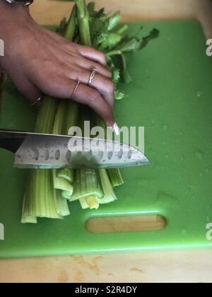 Häckseln Selleriestangen auf einem Schneidebrett in der Küche Stockfoto