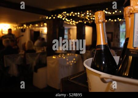 Flaschen Prosecco wartet geöffnet werden, auf eine Bar, während eines festlichen Party mit sitzen die Gäste gerade eine Band, geht auf den Hintergrund. Stockfoto