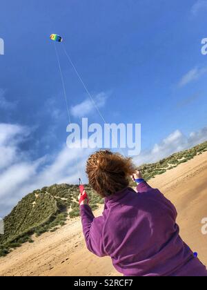 Eine Frau flying a Kite auf Alnmouth Strand Stockfoto