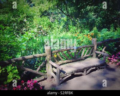 Natürliche Holzbank und Zaun in einer ländlichen Umgebung in der Nähe von Shakespeare Garden, Central Park, New York City, USA Stockfoto