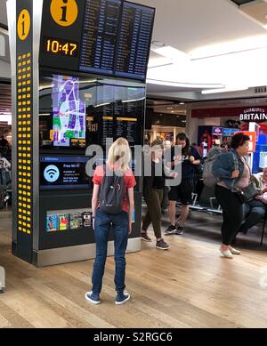 Teenage Mädchen an der Anzeigetafel am Flughafen Heathrow suchen Stockfoto