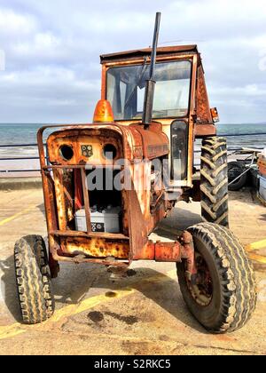 Rusty old seaside Traktor geparkt auf einem Küsten Helling Stockfoto