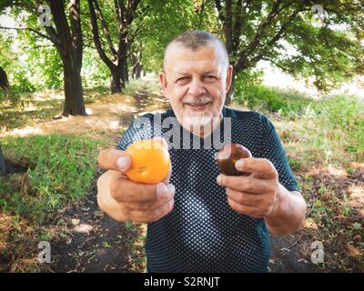 Outdoor Portrait von lächelnden älteren Mann, die zwei unterschiedliche Art der Tomate Stockfoto